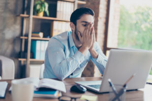 Joven frente a la laptop con gesto de preocupación por la cuesta de enero