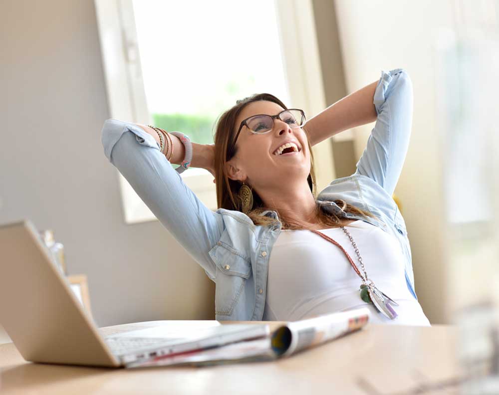 Mujer joven disfrutando de su libertad financiera en su oficina en casa